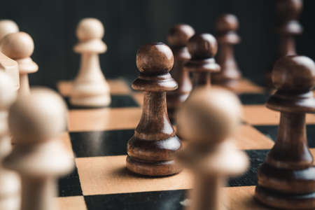 Chess pieces on the board. Black wood background behind.の写真素材