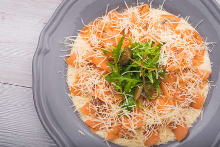 white dish with carpaccio and cheese on white wood backgroundの写真素材