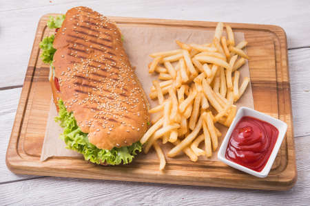 burger and fries with ketchup sauce on wood boardの写真素材
