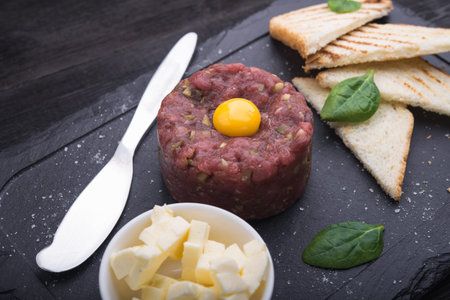 steak tartare with bread and egg on stone boardの写真素材