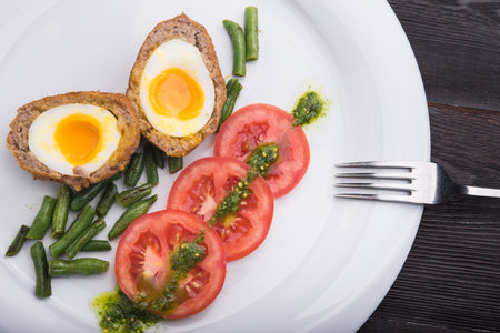 hard boiled egg with tomato and bean on white plateの写真素材