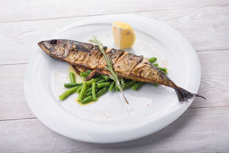 baked fish with lemon and green beans on white backgroundの写真素材