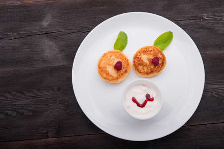 children's menu. pancakes with cottage cheese with cream and raspberryの写真素材