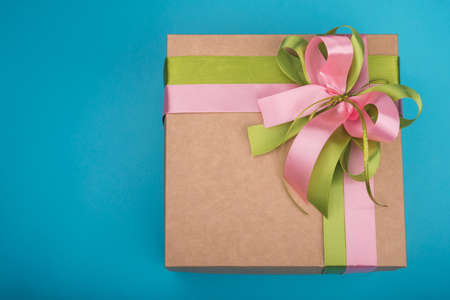 Carton gift box with rose and green ribbon on blue backgroundの写真素材