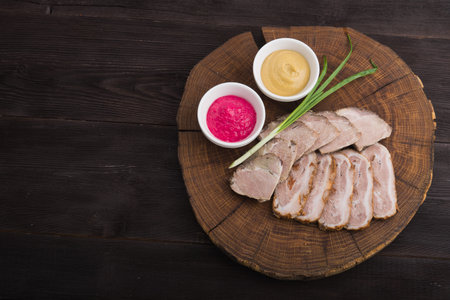 sliced ham and meat with sauces on wood board