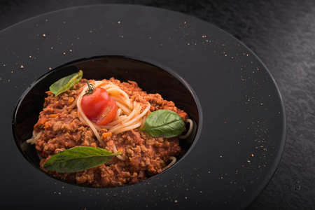 pasta tagliatelle with meat, tomato and basil at black dish.の写真素材