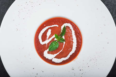 diet tomato soup with leaf of basil on black table. restaurant foodの写真素材