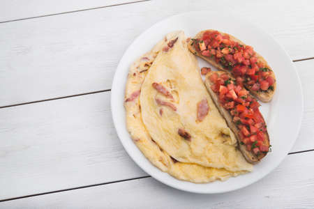 delicious and hearty breakfast of omelet and toast on white wood tableの写真素材