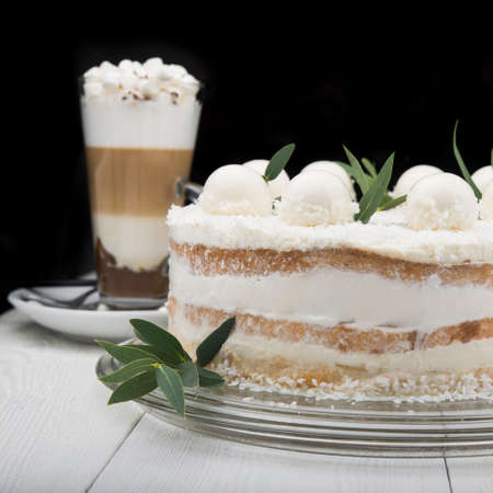 tasty coconut cake with cream vanilla balls on white wood table and black backgroundの写真素材