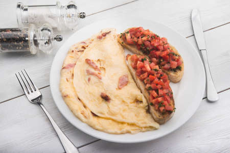 delicious and hearty breakfast of omelet and toast on white wood tableの写真素材