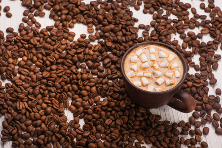 vintage coffee cup with hot dring and tasty marshmallow, roasted beans on wooden tableの写真素材