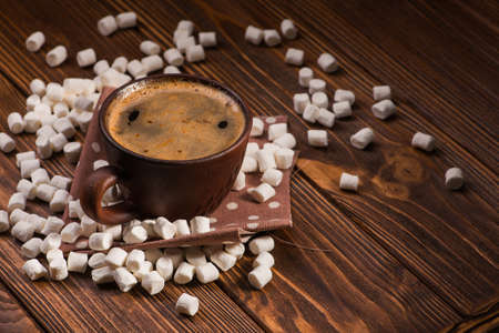 vintage coffee cup with hot dring and tasty marshmallow, roasted beans on wooden tableの写真素材