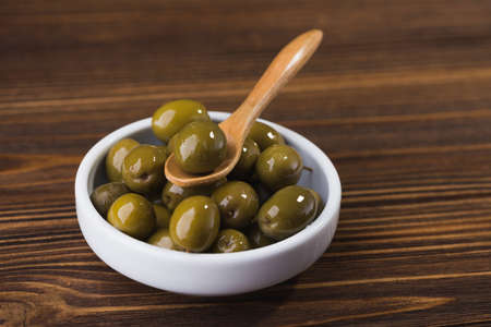 fresh olives in white bowl on wooden tableの写真素材