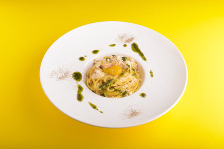 tasty italian spaghetti pasta with parmesan on a dish, yellow table