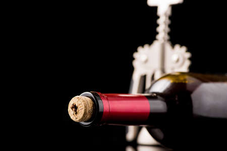 Red wine bottle open with corkscrew isolated on a black backgroundの写真素材