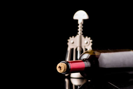 Red wine bottle open with corkscrew isolated on a black backgroundの写真素材