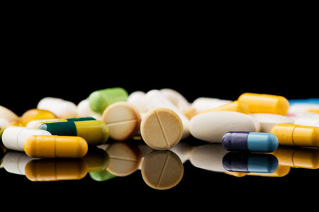 white pills on black glass background. medical pharmacy
