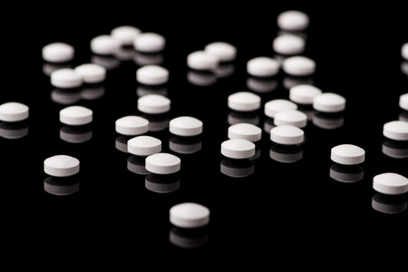 white pills on black glass background. medical pharmacyの写真素材
