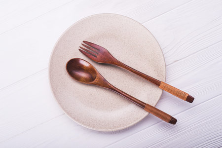 Empty white plate with spoon and fork on wood table. view from topの写真素材