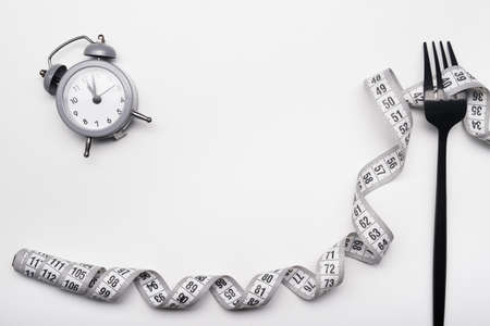 Diet concept, black fork and measuring tape isolated on white backgroundの写真素材