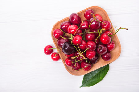 fresh red cherry fruit in plate on wood table. top viewの写真素材