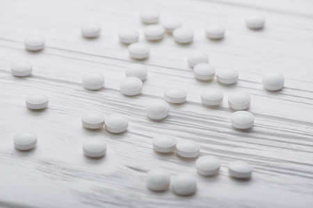 Pile of white medicine pills on wood tableの写真素材