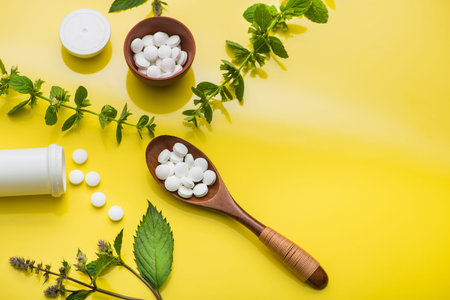 Herbal medicine pills with leaf and bottle on yellow background. top view