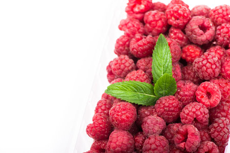 fresh red raspberry wuth green leaf isolated on white background