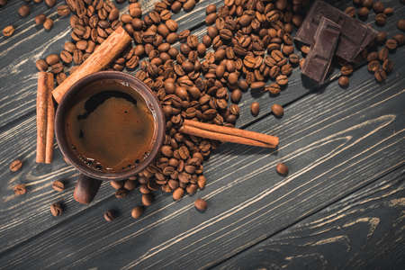 Cup of coffee with roasted beans and cinnamon on a wooden table. top viewの写真素材
