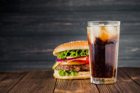 american snack with big burger and glass cola on wooden table