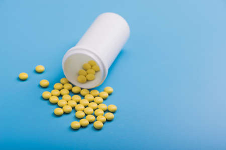 Yellow medical pills on a blue background. medicine conceptの写真素材