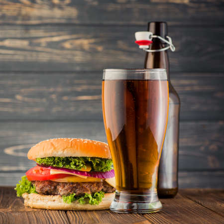 Tasty big burger and beer glass on wood tableの写真素材