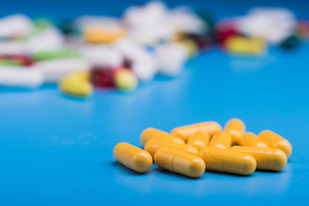 Yellow medical pills or capsule on blue table