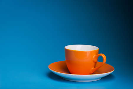 empty orange coffee cup on a blue backgroundの写真素材