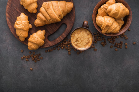 delicious croissant with a cup of coffee, roasted beans on vintage concrete background, top viewの写真素材