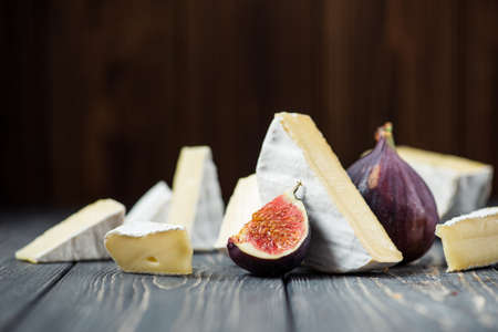 white pieces of camembert or brie cheese with fig on a wooden tableの写真素材