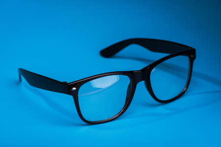 black modern glasses on a blue backgroundの写真素材