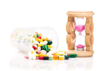 concept of medical pills and hourglass isolated on white background. time to take antibioticの写真素材