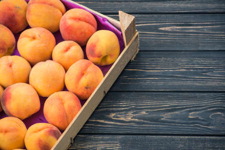 Fresh and ripe peaches in a wooden boxの写真素材