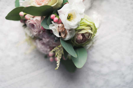 wedding flower bouquet on white table. rose flowers decoration. golden ringsの写真素材