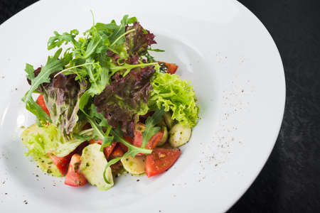 Vegetarian salad with tomatoes and mozzarella cheese in white plateの写真素材