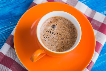 orange cup of coffee with napkin on blue retro tableの写真素材