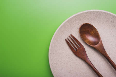 Empty white plate with spoon and fork on green background. view from topの写真素材