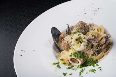 seafood pasta with squid and mussels in a white plate. dish at the restaurantの写真素材