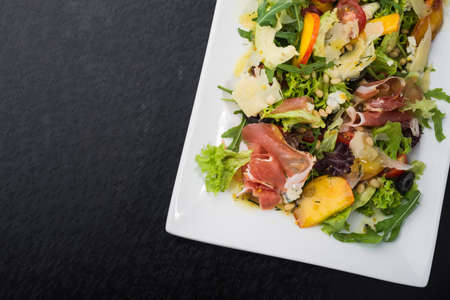 tasty salad with prosciutto, salan and peach on white dish. vegetarian healthy foodの写真素材