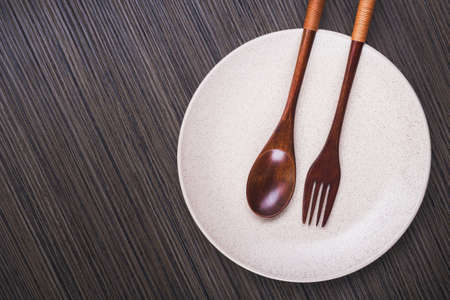 Empty white plate with spoon and fork on wood table. view from topの写真素材