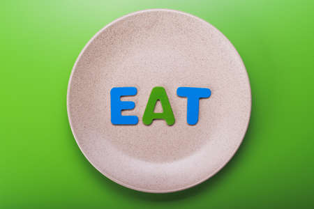 Empty ceramic plate with eat letter on background. top viewの写真素材