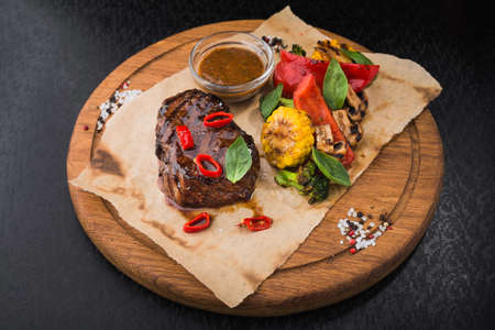 hot steak with vegetables and pepper, corn and mushrooms on wooden board. delicious snack at the restaurantの写真素材