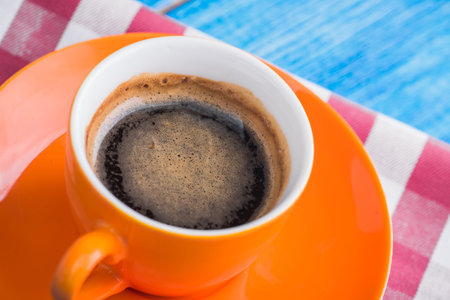 orange cup of coffee with napkin on blue retro tableの写真素材