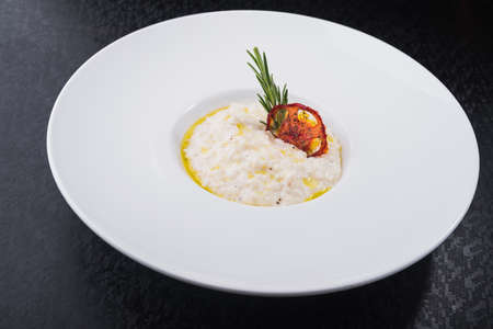 classic rice risotto with rosemary branch in white plateの写真素材